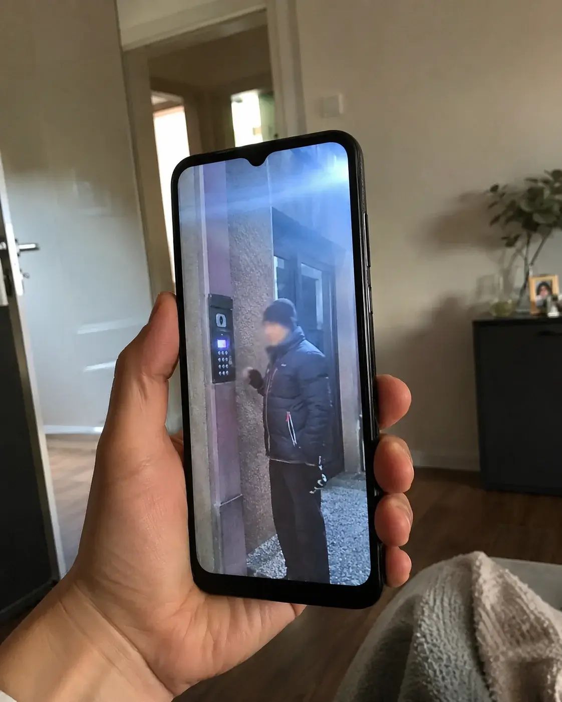 Telefon stanara prikazuje video poziv osobe pred ulazom u zgradu