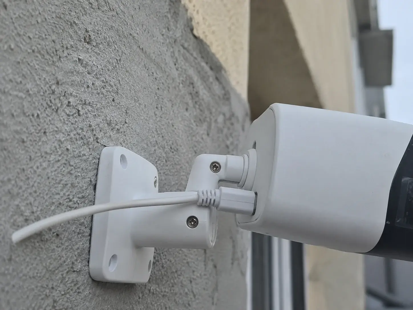 Mrežni kabl priključen na IP kameru montiranu na zid