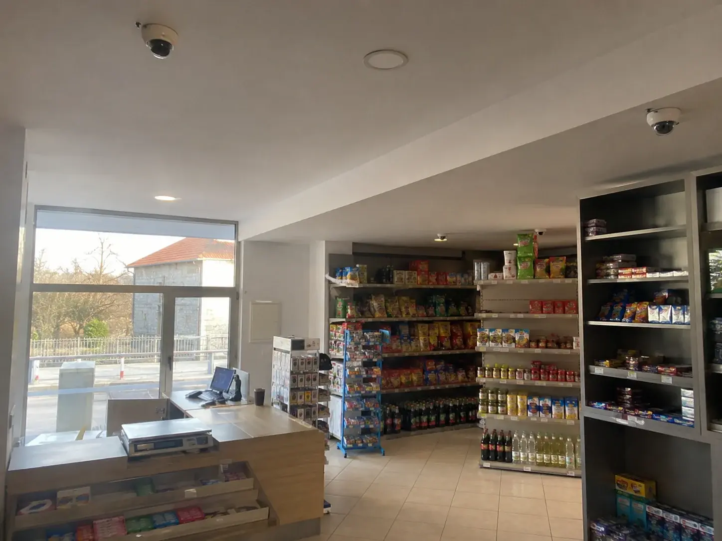 Unutrašnjost prodavnice sa kamerama montiranim na plafon iznad polica i kase