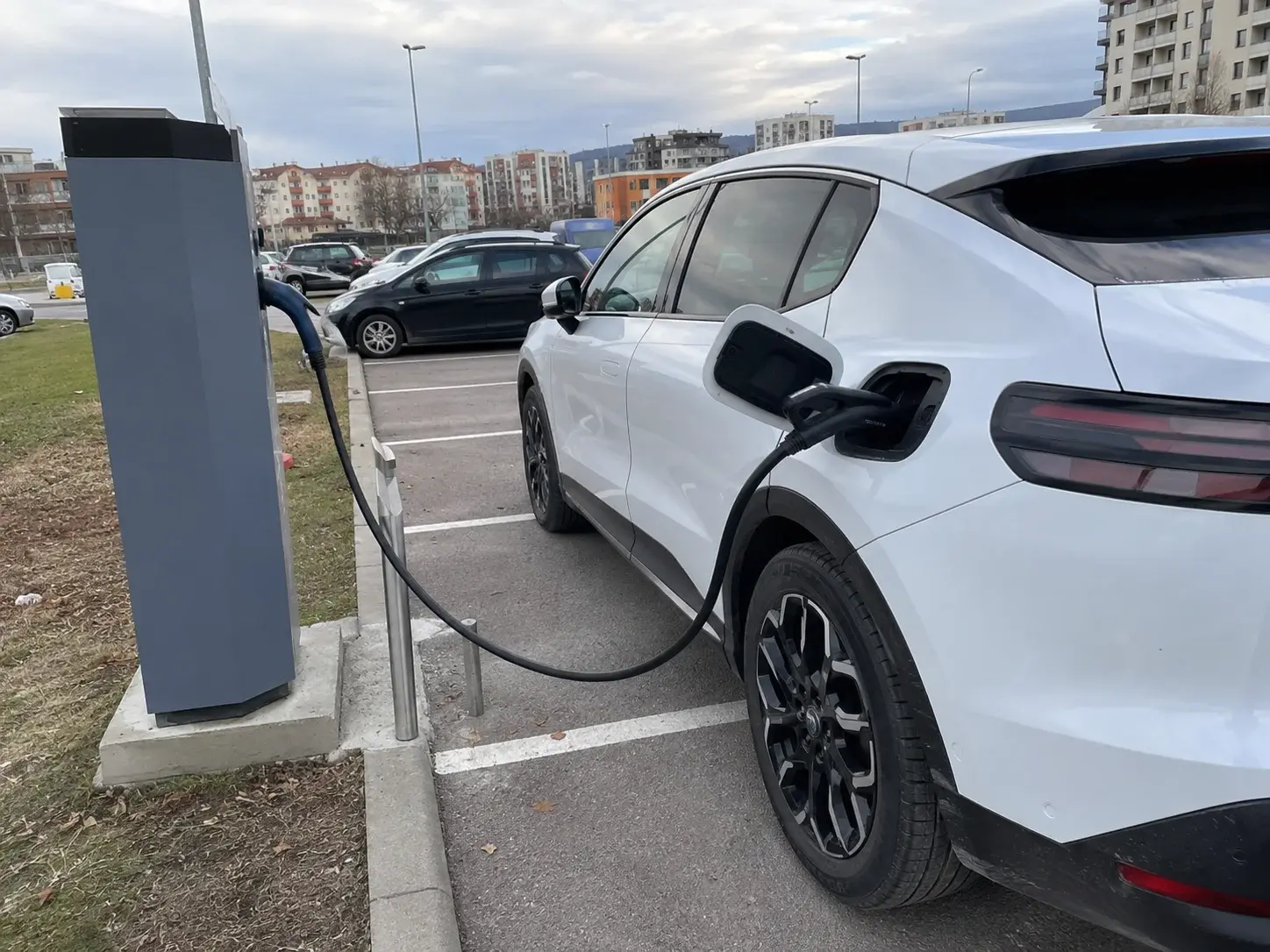 Električni automobil priključen na javnu brzu punionicu na parkingu