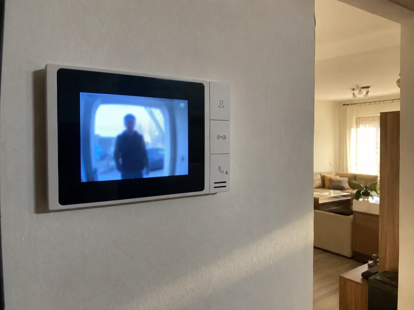 Monitor video interfona u predsoblju sa likom posetioca na ekranu