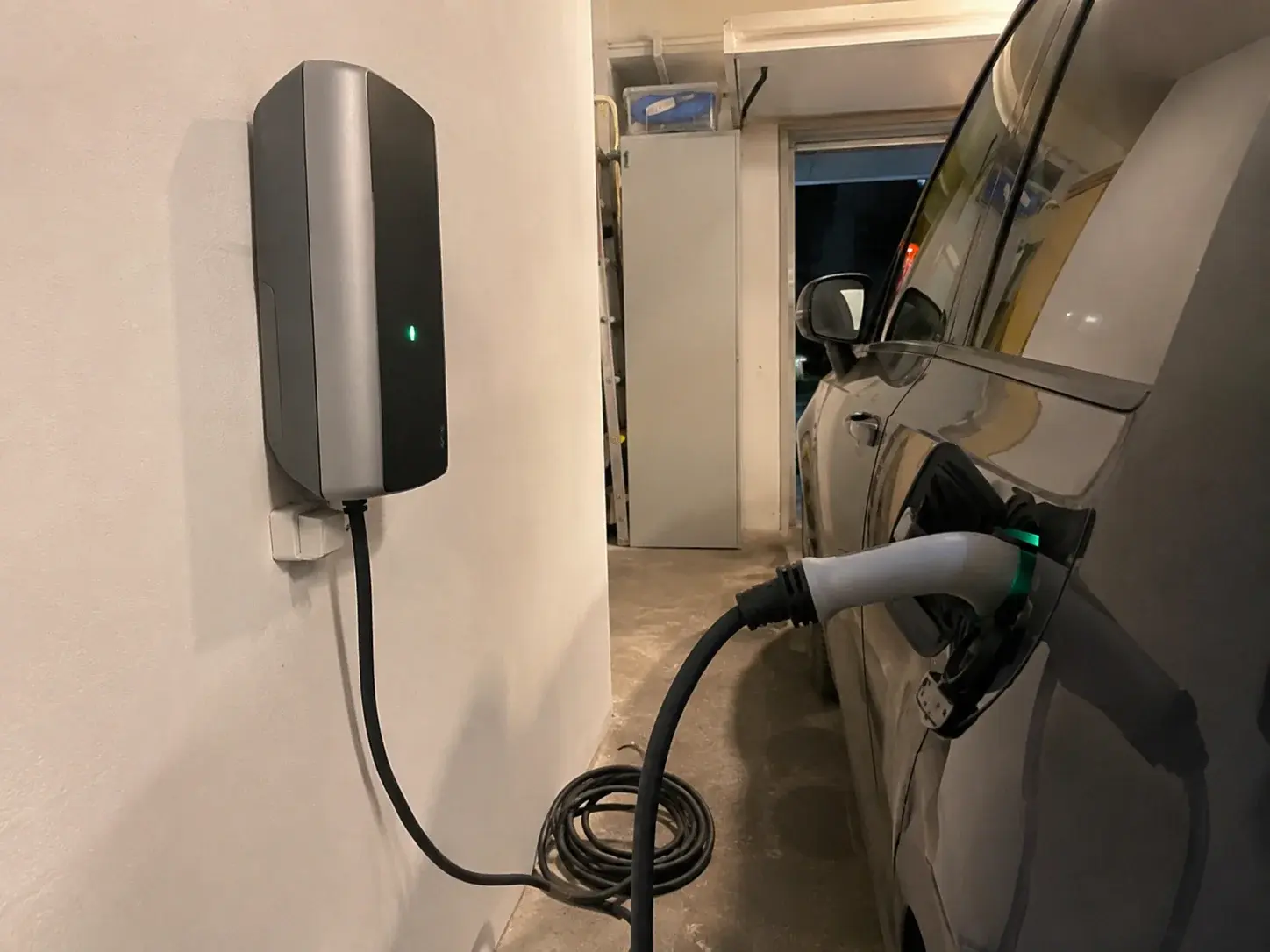 Zidni kućni punjač priključen na električni automobil u garaži uveče