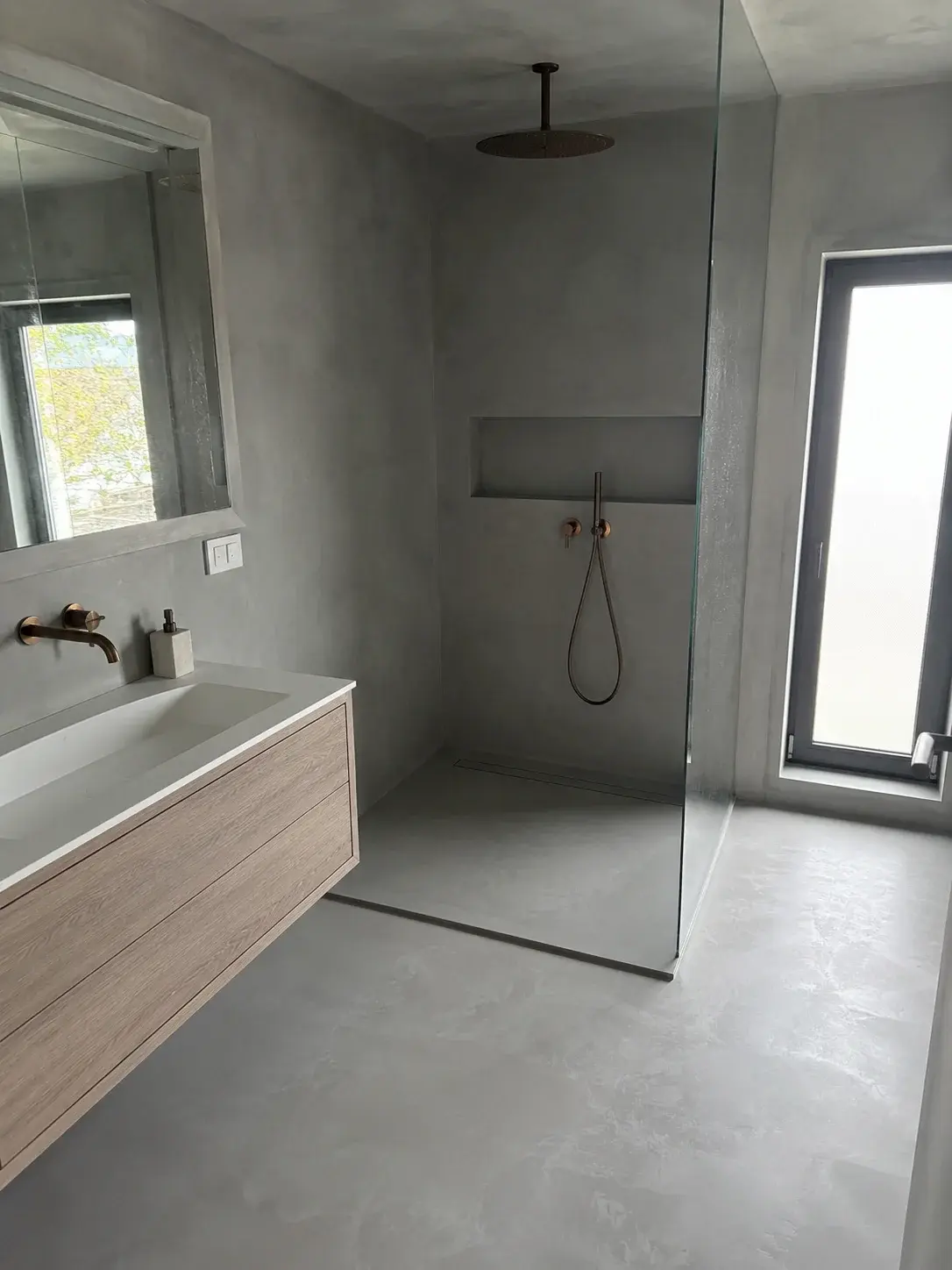 Moderno kupatilo sa bešavnim zidovima i podom u sivom mikrocementu