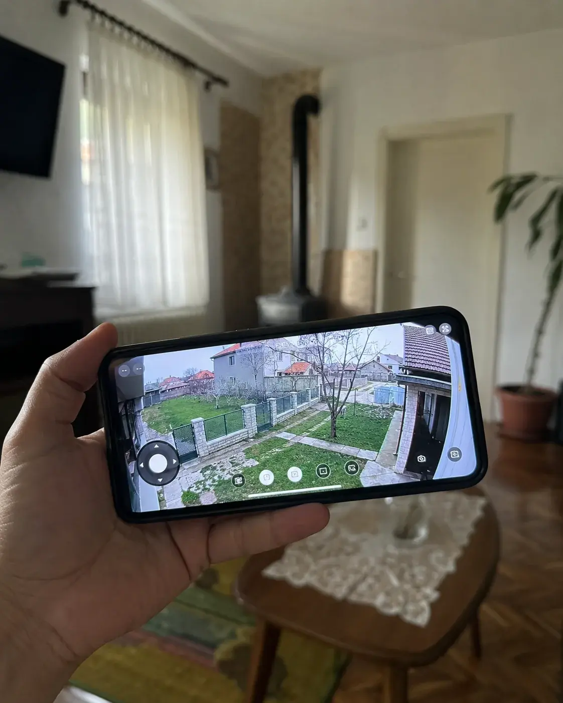 Telefon prikazuje živu sliku sa kamere dvorišta u ruci korisnika