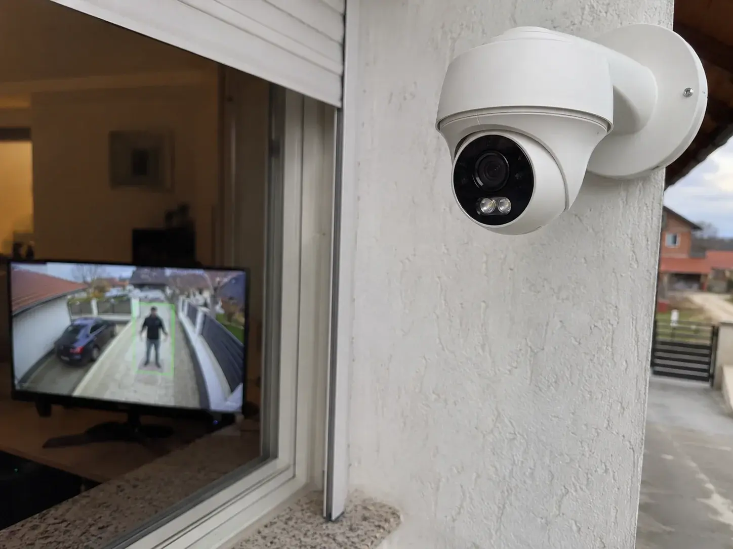 Moderna AI kamera usmerena na prilaz, osoba uokvirena detekcijom na monitoru