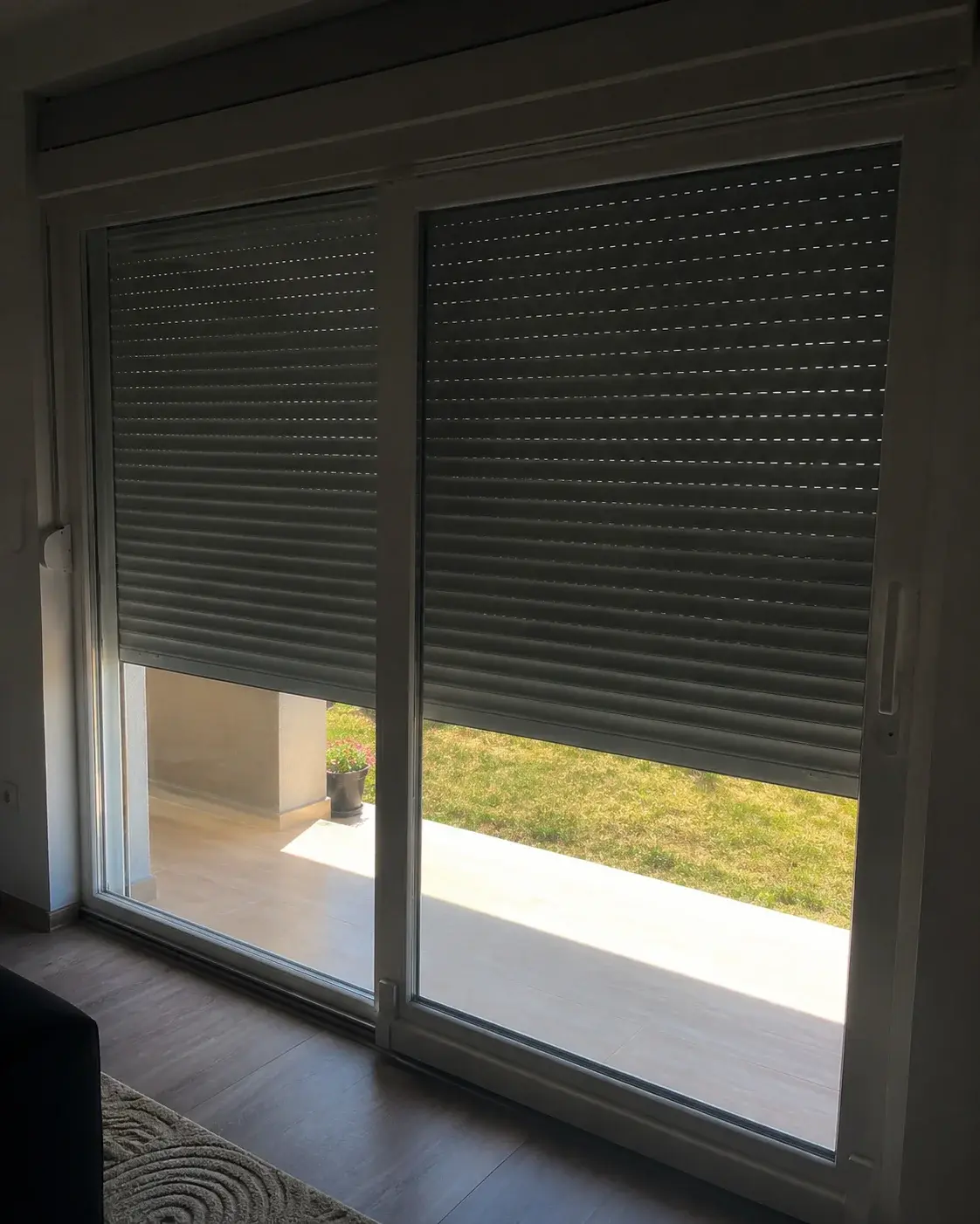 Terasna vrata sa spuštenom roletnom koja zasenčuje sobu u letnje podne