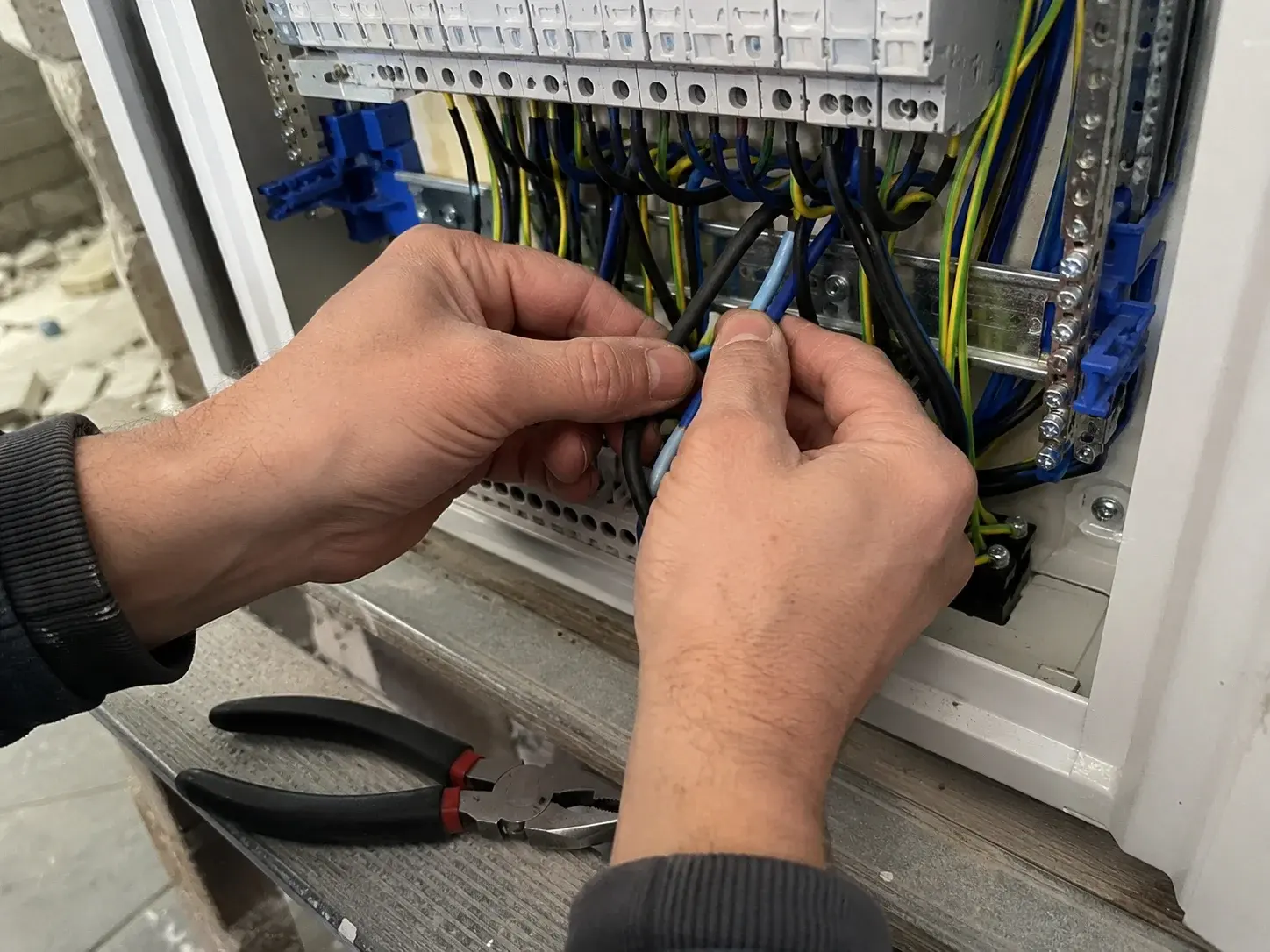 Elektroinstalater povezuje provodnike u novi razvodni orman