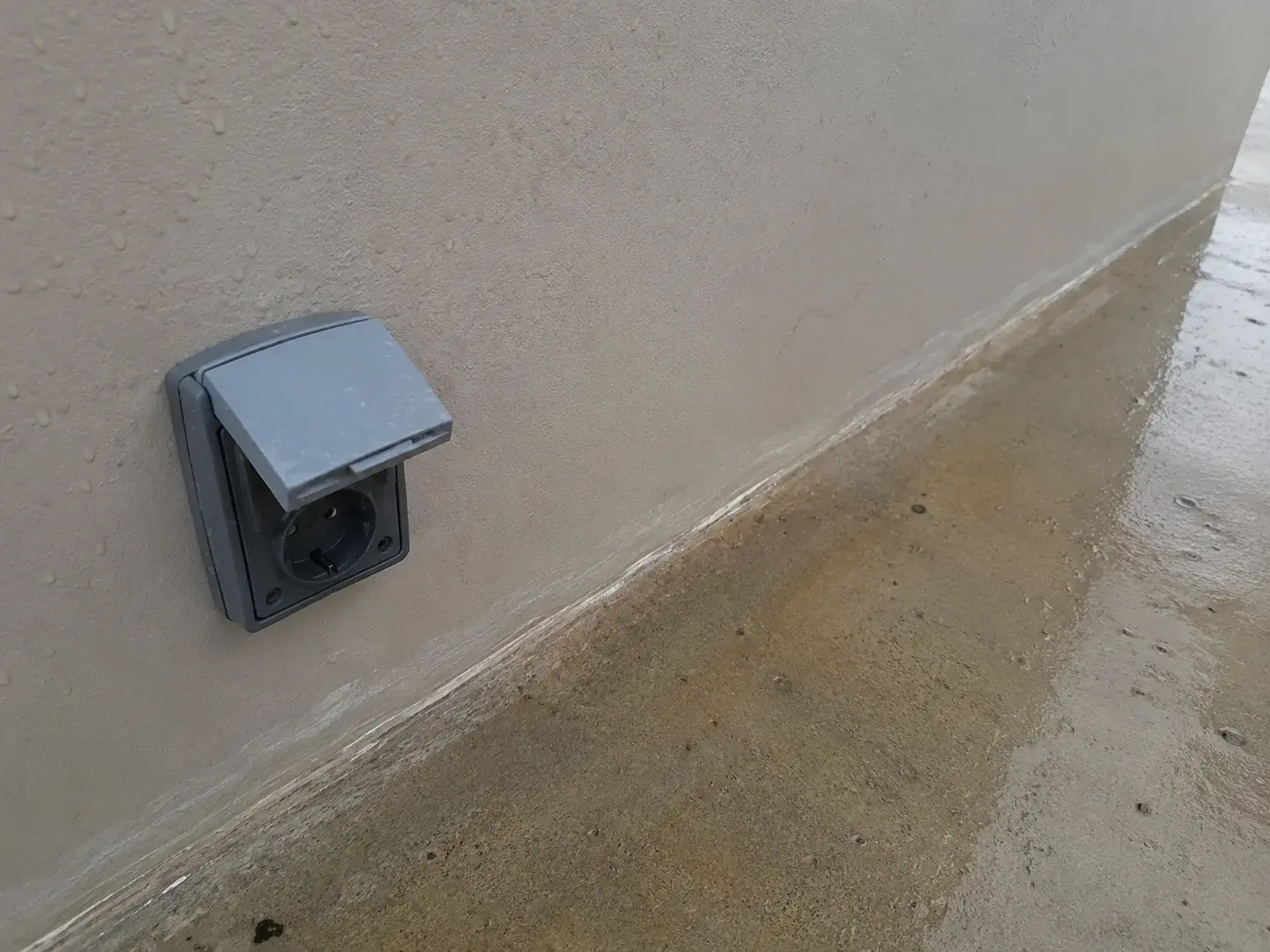 Spoljna utičnica sa zaštitnim poklopcem na vlažnom zidu terase