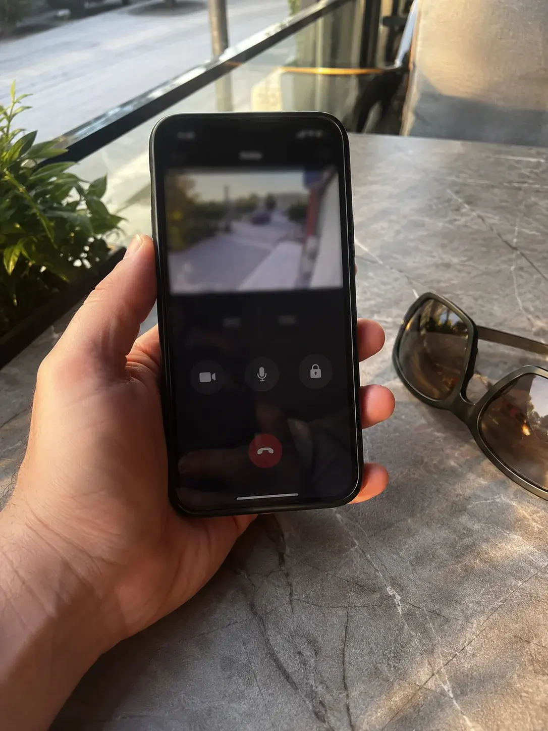 Ruka drži telefon sa aplikacijom video interfona dok je korisnik van kuće