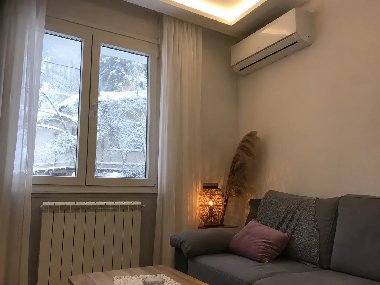 Dnevna soba sa klimom i radijatorom u istom prostoru tokom zime