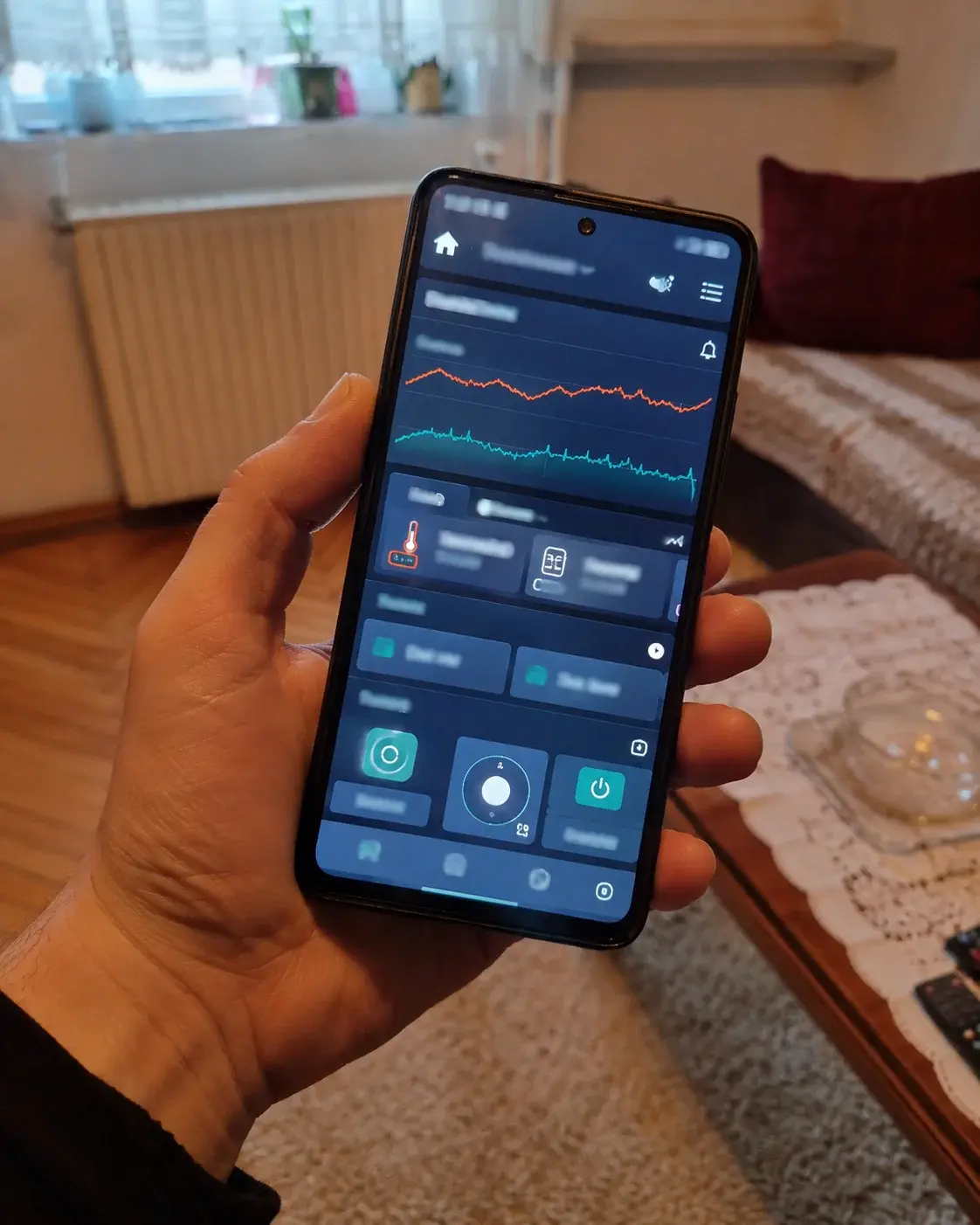 Telefon sa aplikacijom za daljinsko upravljanje grejanjem u ruci